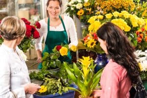 Florist woman preparing bouquet customers flower shop market happy