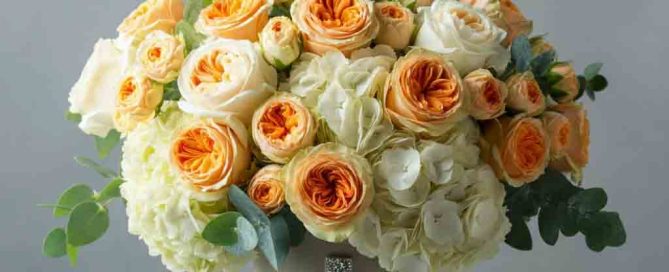 This beautiful bouquet features premium roses, spray roses, hydrangea and more in soft peaches and whites. Delivered in a Shining Cross vase